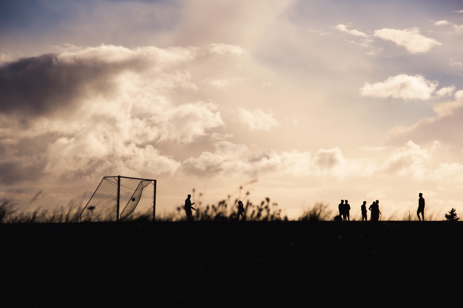 Silhouettes de jeunes footballeurs sur un terrain au coucher du soleil
