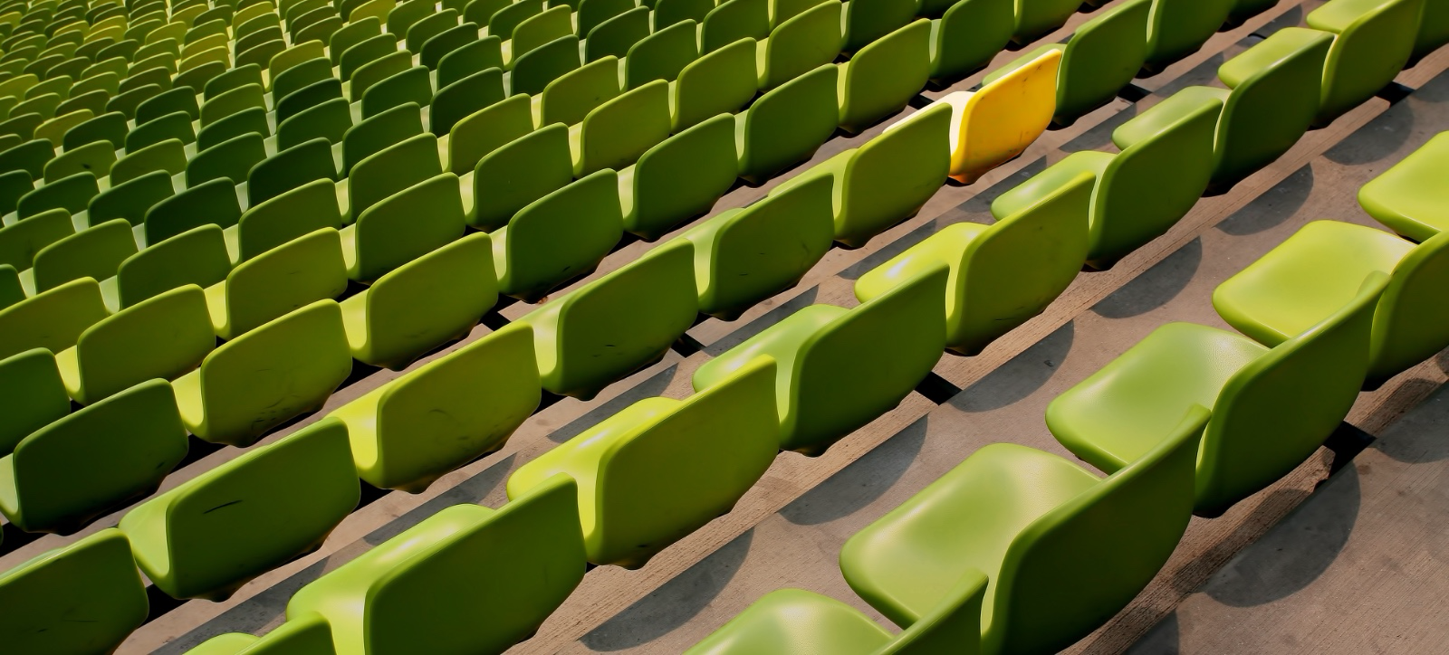 Rangées de sièges de stade verts avec un siège jaune distinct
